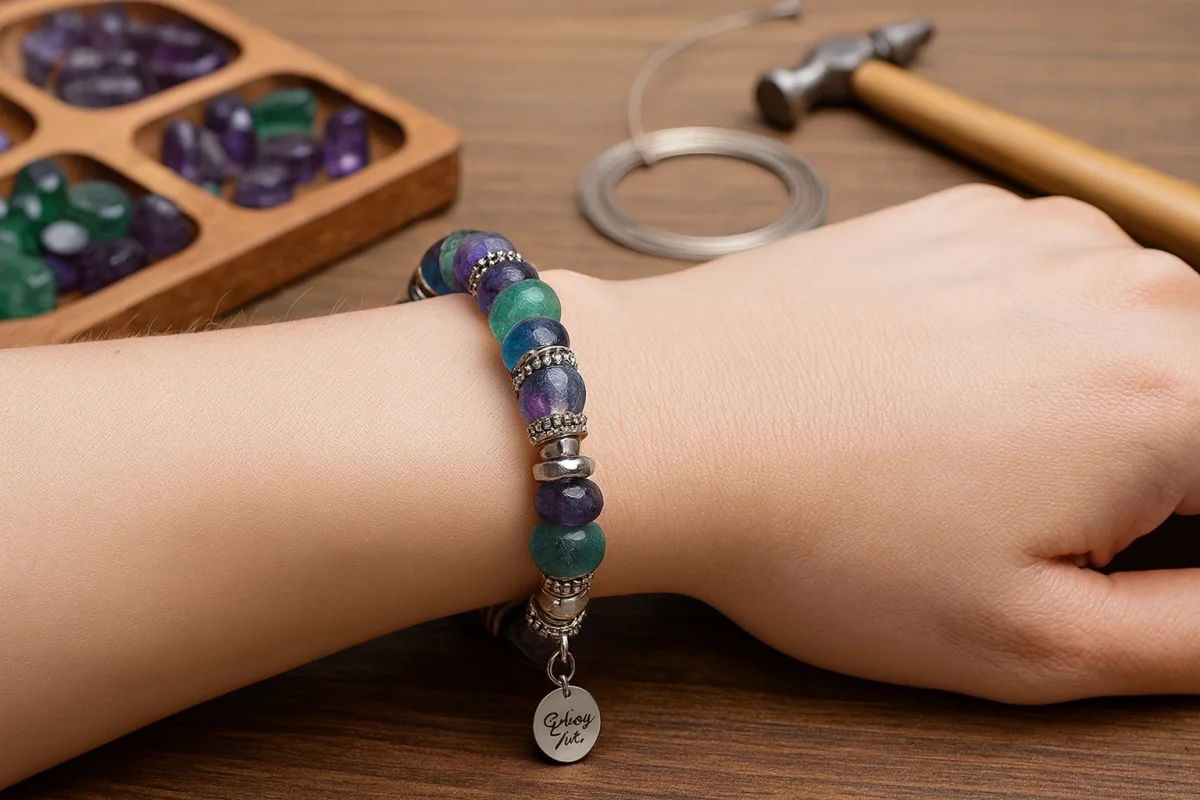 دستبند ساختهشده از مهرههای سنگ فلوریت سبز و بنفش روی مچ دست.